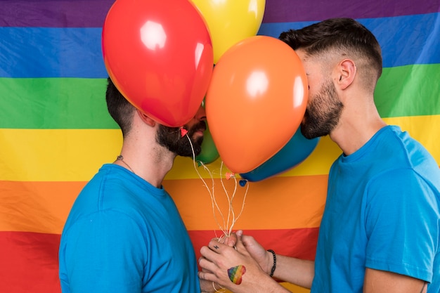Coppia omosessuale con palloncini sulla bandiera arcobaleno