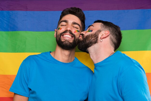 Homosexual man kissing boyfriend on LGBT flag