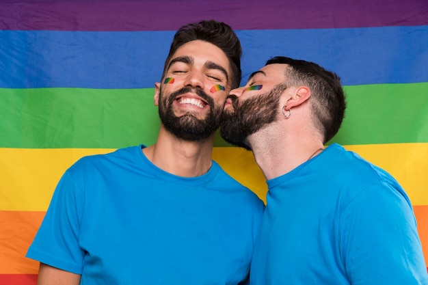 Гомосексуальный мужчина целует парня на флаге ЛГБТ