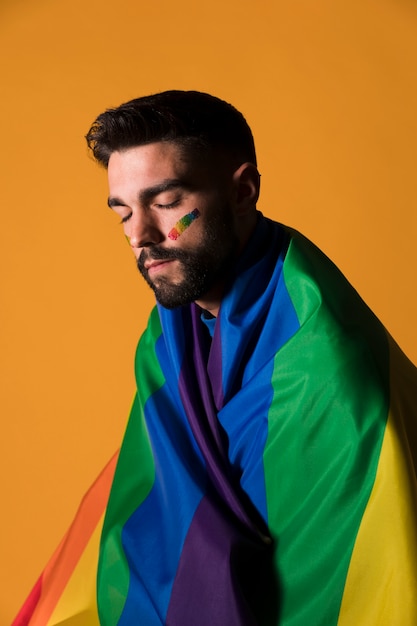 同性愛者の男性がLGBTの虹色の旗に包まれて