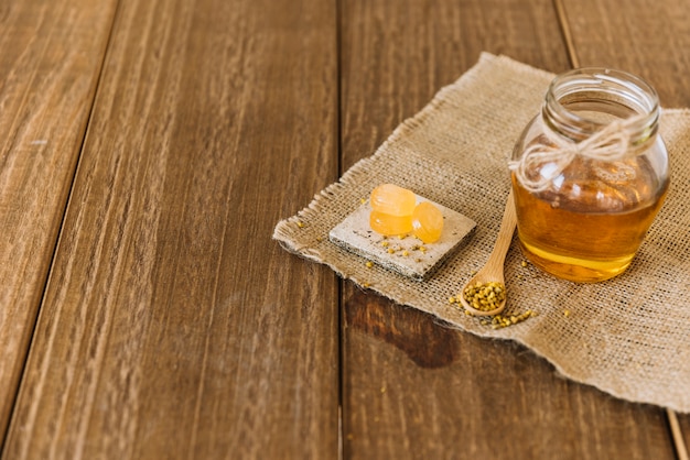 Foto gratuita miele; semi di polline d'api e caramelle sul panno di sacco su sfondo in legno