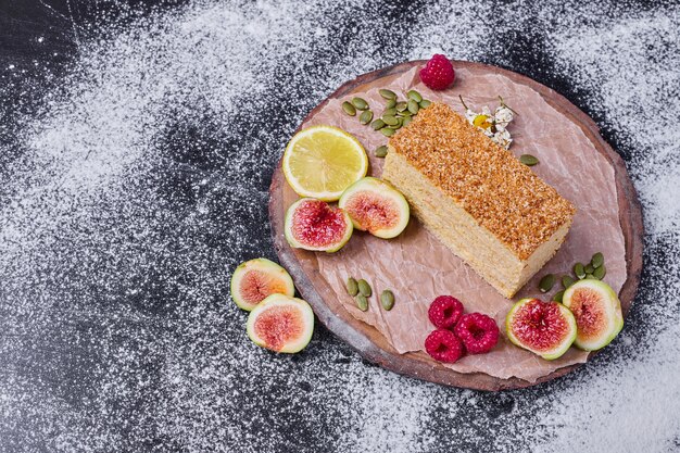 Honey cake on dark table with figs and raspberries. 
