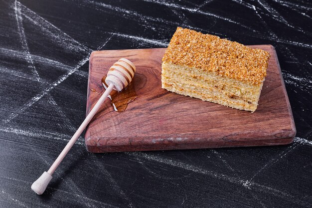 Honey cake with honey spoon on dark background. 