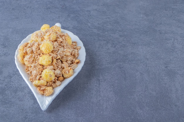 Honey corn ring with muesli in a plate, on the marble table.