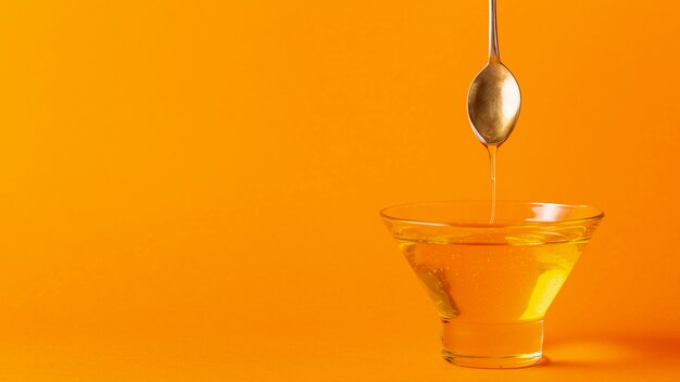 Honey dripping off spoon in bowl with copy space