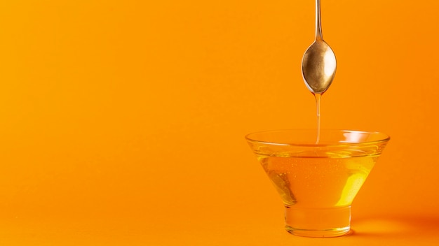 Honey dripping off spoon in bowl with copy space