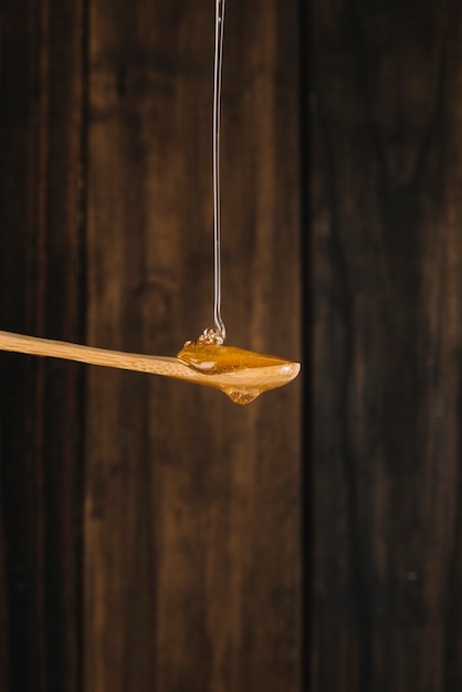 Free photo honey dripping on wooden spoon