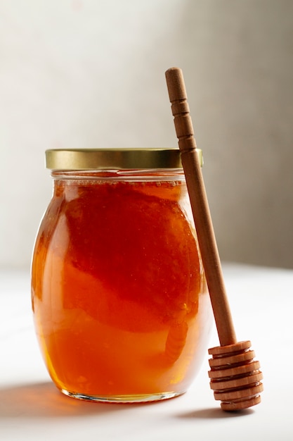 Free photo honey jar with wooden honey dipper