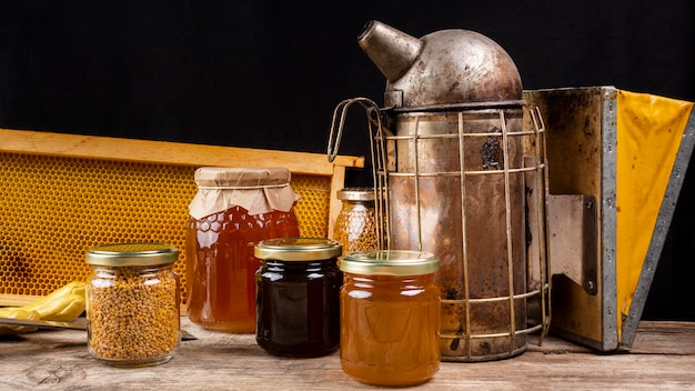 Foto gratuita vasetti di miele con fumatore di api e favo