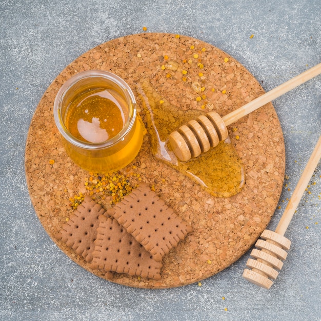 Honey pot; wooden dipper; biscuits and bee pollen on cork coaster