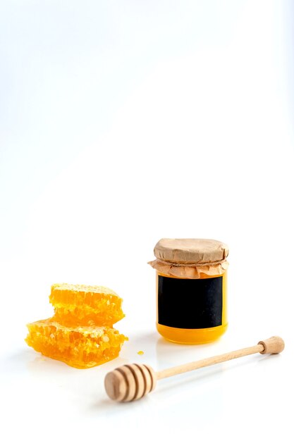 Honey products composition. Honey in a jar, honeycomb and special spoon. White wall