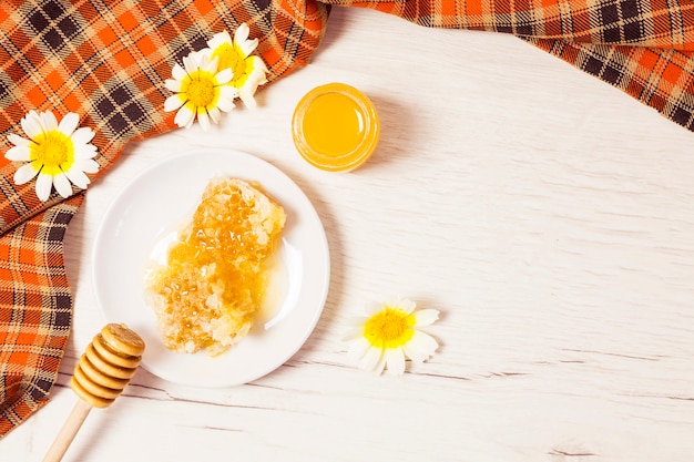 Honeycomb and honey with checkered table cloth on wooden desk