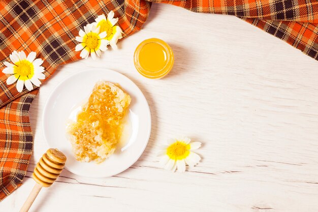 Honeycomb and honey with checkered table cloth on wooden desk