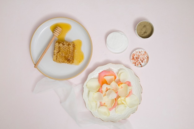 Free photo honeycomb; petals; cotton pad; rhassoul clay; rock salt and herbal ground on white background