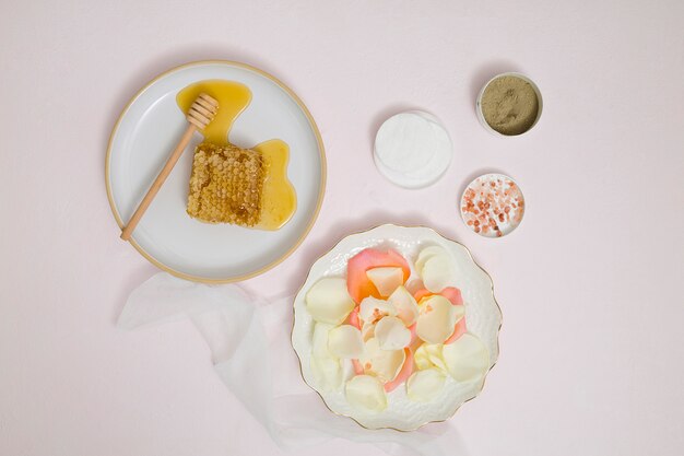 Honeycomb; petals; cotton pad; rhassoul clay; rock salt and herbal ground on white background