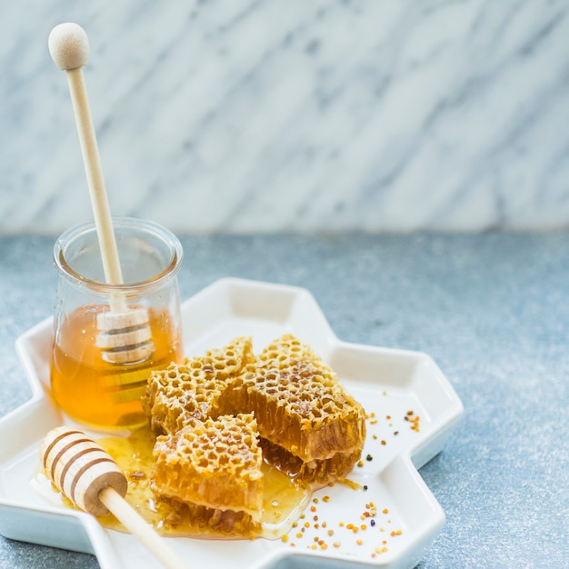 Honeycomb pieces and honey jar on floral tray