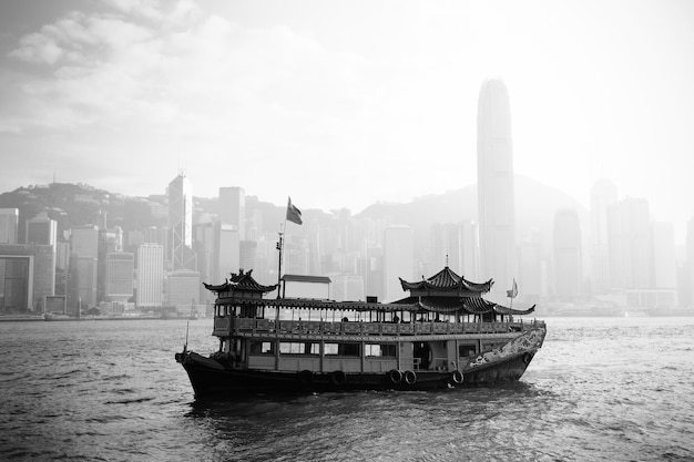 Hong Kong skyline with boats in Victoria Harbor in black and white.