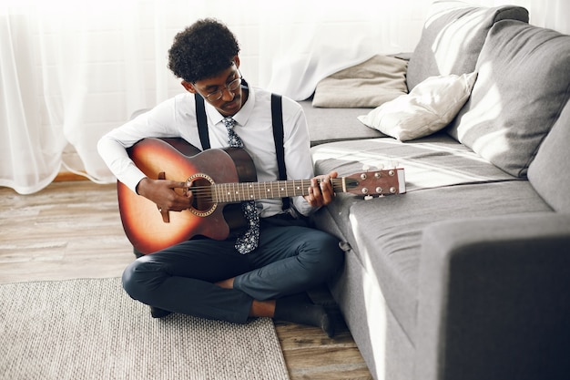 Hoobies concept. indian young man in tights sitting in the living room. musician playing the guitar.