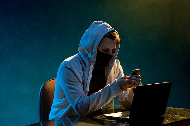 Hooded computer hacker stealing information with laptop