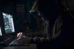 Free photo hooded hacker stealing information from a computer dark background