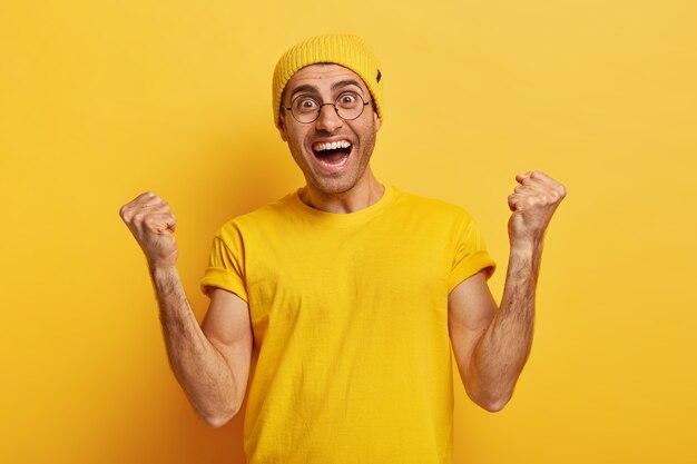 Hooray! Overemotive happy man makes fist pump from success and happiness, cheers achieving goal
