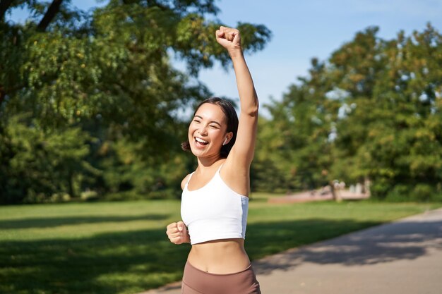 Foto gratuita evviva vittoria sorridente ragazza asiatica che trionfa celebrando il successo correndo fino alla fine gridando fr