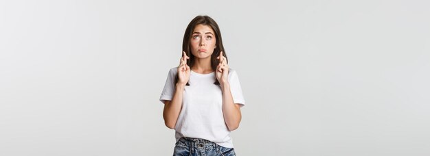 Hopeful cute brunette girl cross fingers good luck looking up and making wish