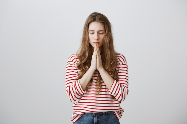 Hopeful girl holding hands in pray, pleading