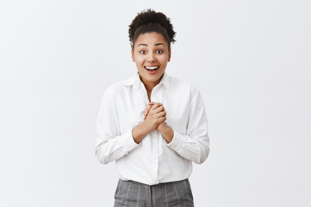 Hopeful and happy african american woman clasp hands together and smiling excited