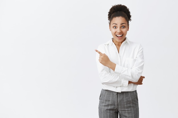 Hopeful and happy young african-american woman smiling joyful and pointing upper left corner