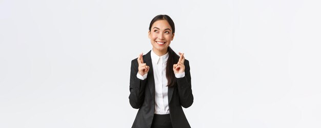 Hopeful optimistic businesswoman having faith in herself believe dreams come true cross fingers for good luck and looking up at sky making wish praying for relish white background