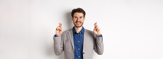 Free photo hopeful smiling businessman looking optimistic cross fingers good luck praying to win waiting for re