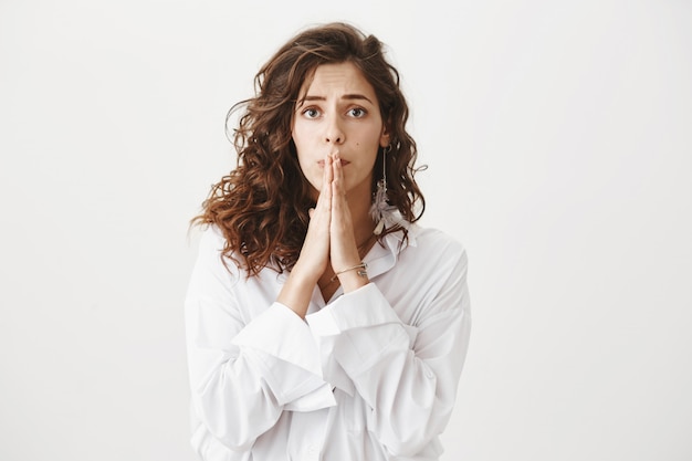 Hopeful worried woman hold hands in pray, looking anxious