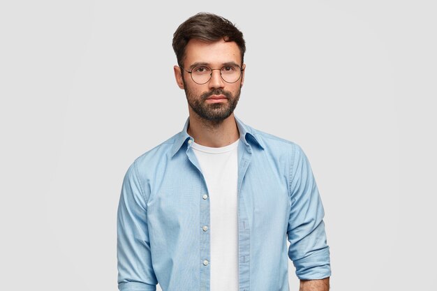 Horiozontal shot of handsome man freelancer with thick bristle, dressed in fashionable shirt