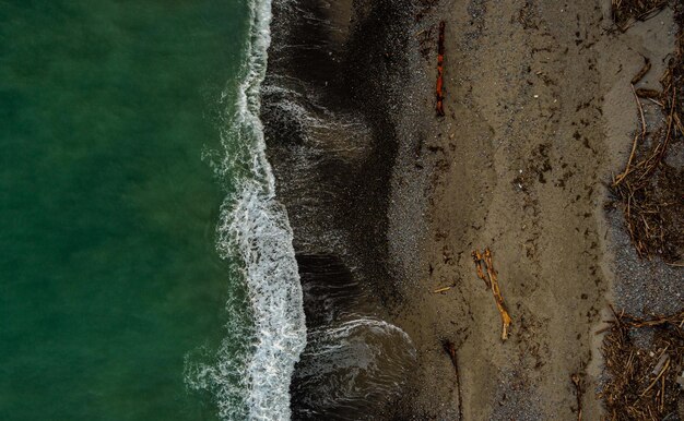 Horizontal aerial view of a foamy ocean hitting the cliffs
