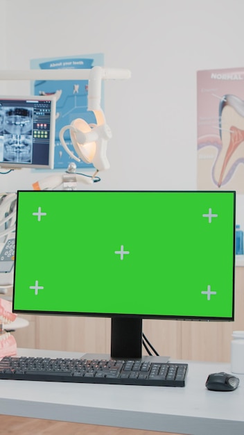 Бесплатное фото Горизонтальный зеленый экран на компьютере в кабинете стоматолога, пока специалисты используют оборудование для стоматологической помощи. монитор с цветным ключом и изолированным шаблоном макета в офисе для ухода за зубами.