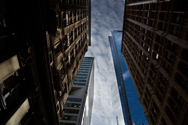Горизонтальный низкий угол обзора отражающих высотных зданий под захватывающим облачным небом