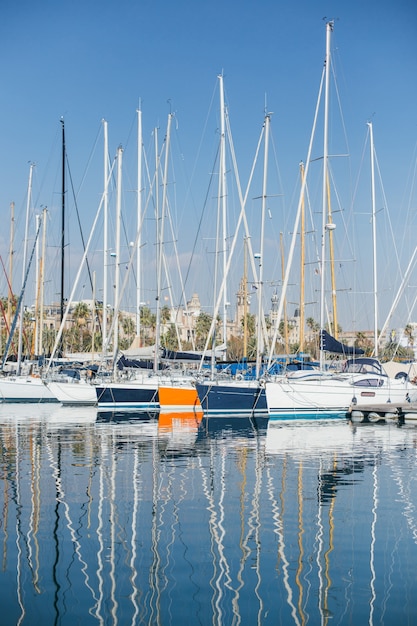 Horizontal photo of luxury and glamorous yachts and sailboats docked or parked in marina port in barcelona, spain