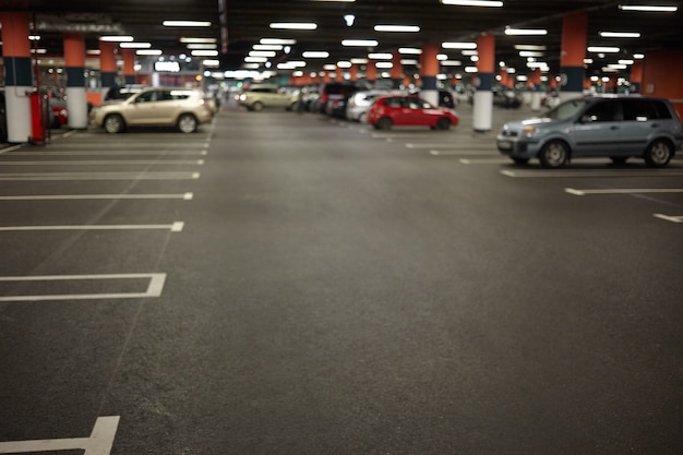 Horizontal picture of car parking or underground garage interior with neon lights and autocars parked. Buildings, urban constructions, space, transportation, vehicle and night city concept