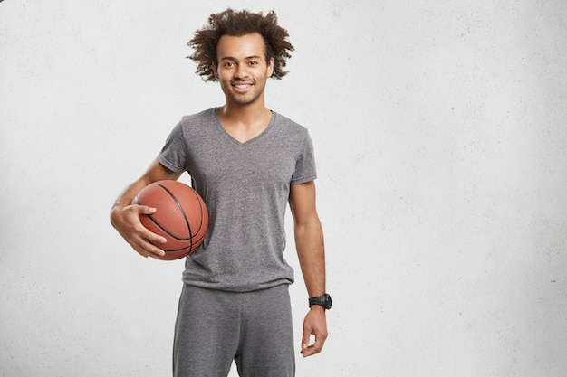 Free photo horizontal portrait of basketball player dressed casually, holds ball,