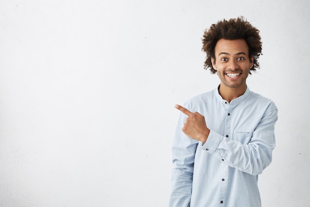 Horizontal portrait of dark-skinned handsome man having broad smile wearing formal white shirt