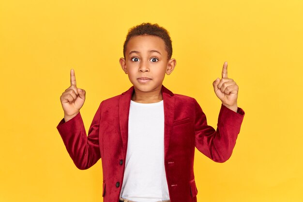 Horizontal portrait of emotional excited eight year old African boy indicating at interesting content