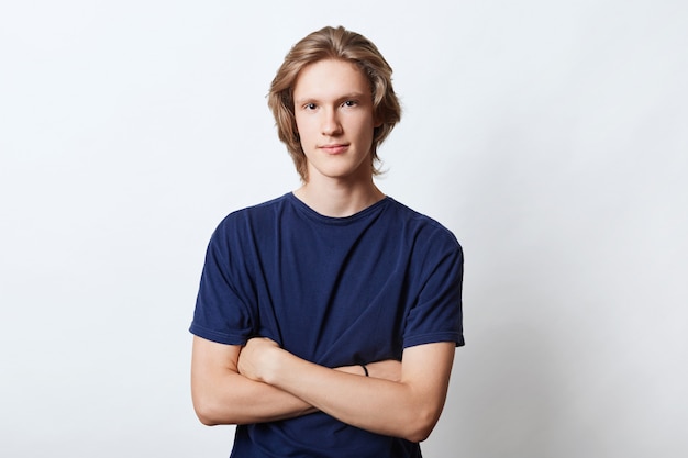 Horizontal portrait of handsome guy with specific appearance, keeping his hands crossed, looking with confidence into camera, isolated on white. Male freelancer or manager going for work