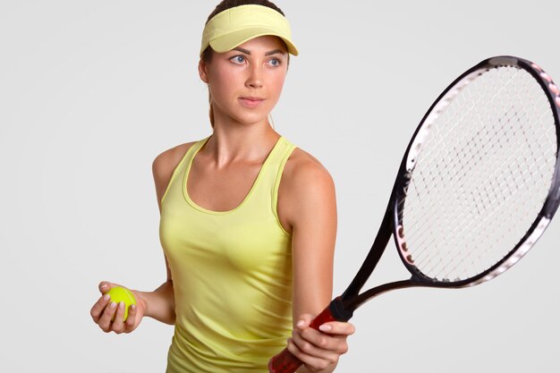 かなりプロの女性テニスプレーヤーの水平方向の肖像画を保持するラケット、お気に入りのショットを作る準備ができて、ボールを保持