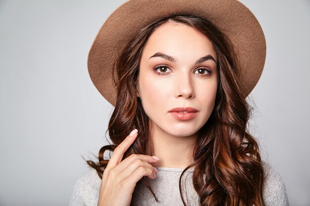 Horizontal portrait of stylish attractive female model wears summer clothes and brown hat with natural makeup