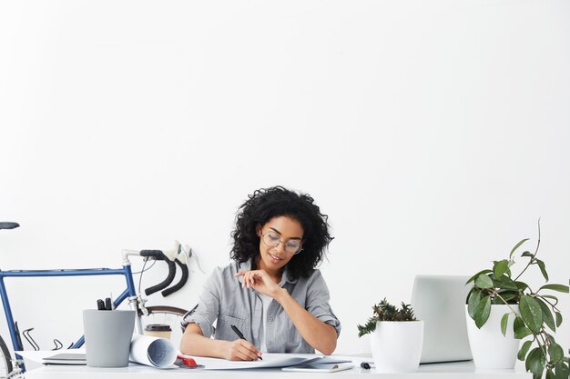 Horizontal portrait of successful young dark-skinned engineer female wearing casual shirt