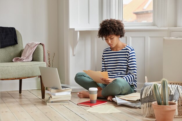 Horizontal shot of administrative manger sits in lotus pose on floor, studies contract