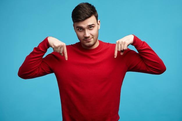 Horizontal shot of attractive young brunette male in casual clothes staring at camera