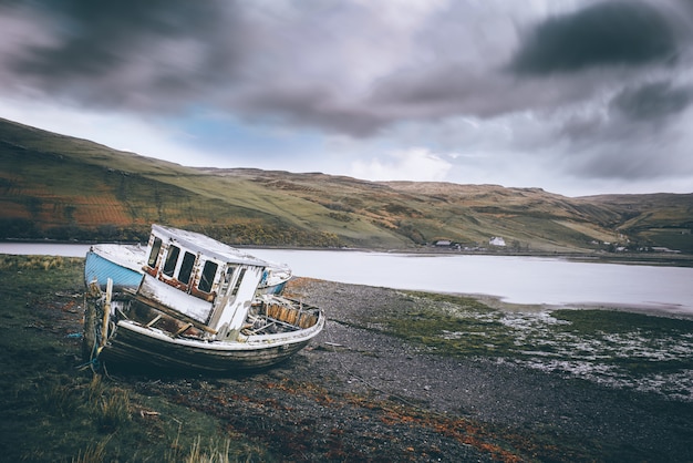 Horizontal shot of a beach with an abandoned boat near the water