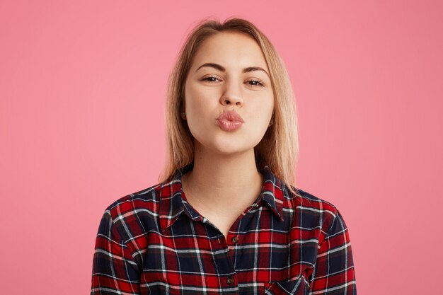 Horizontal shot of beautiful female with rounded lips, going to kiss boyfriend, expresses great love and good feelings